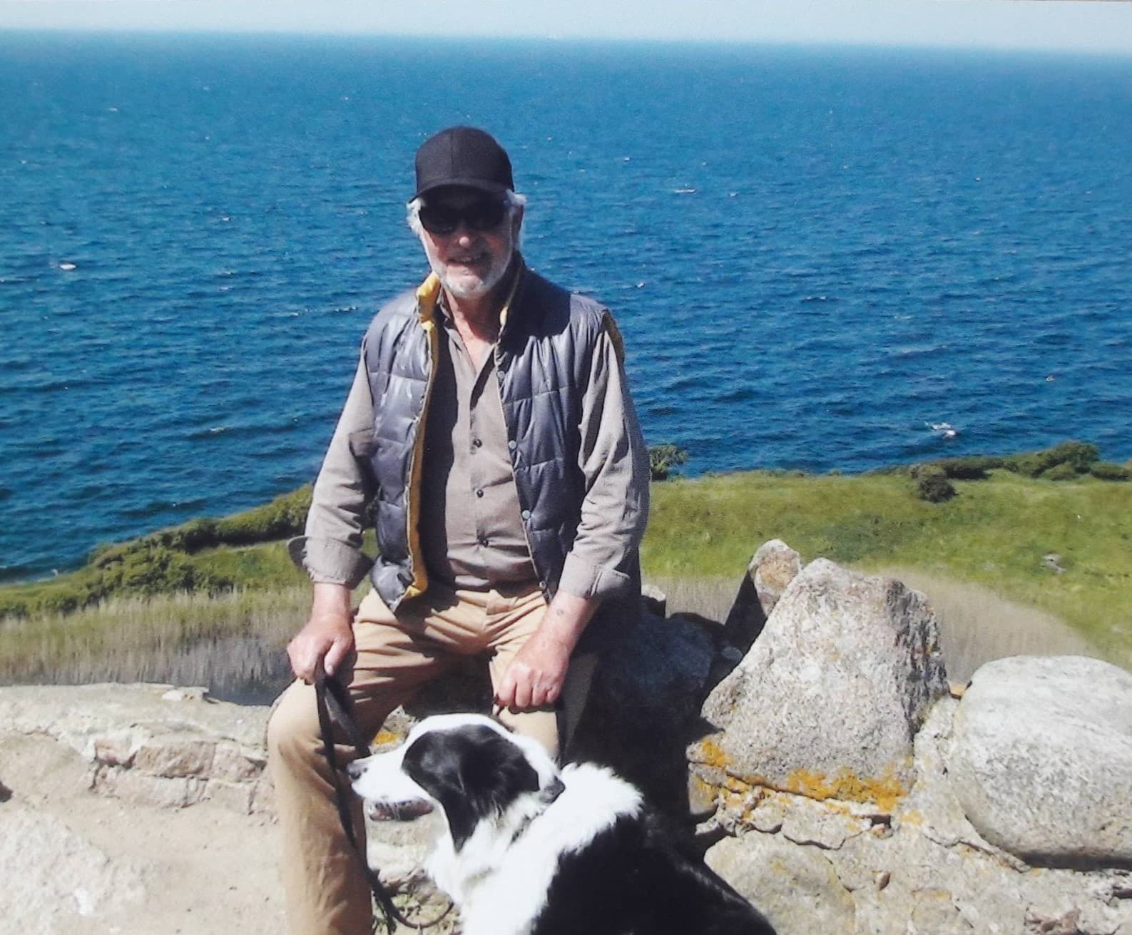 Tommy sidder med border collie ved stranden