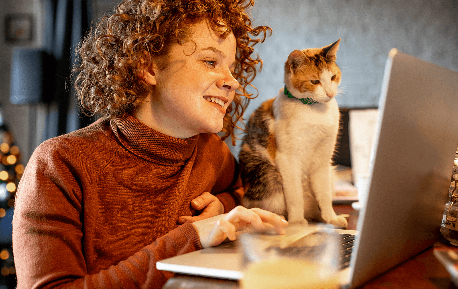 Pige sidder med kat og kigger på computer